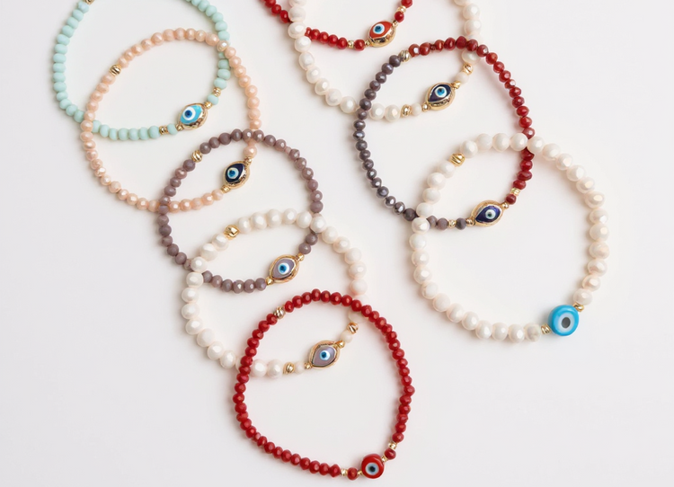 Colorful beaded evil eye bracelets made with natural stone beads and gold accents arranged flat lay