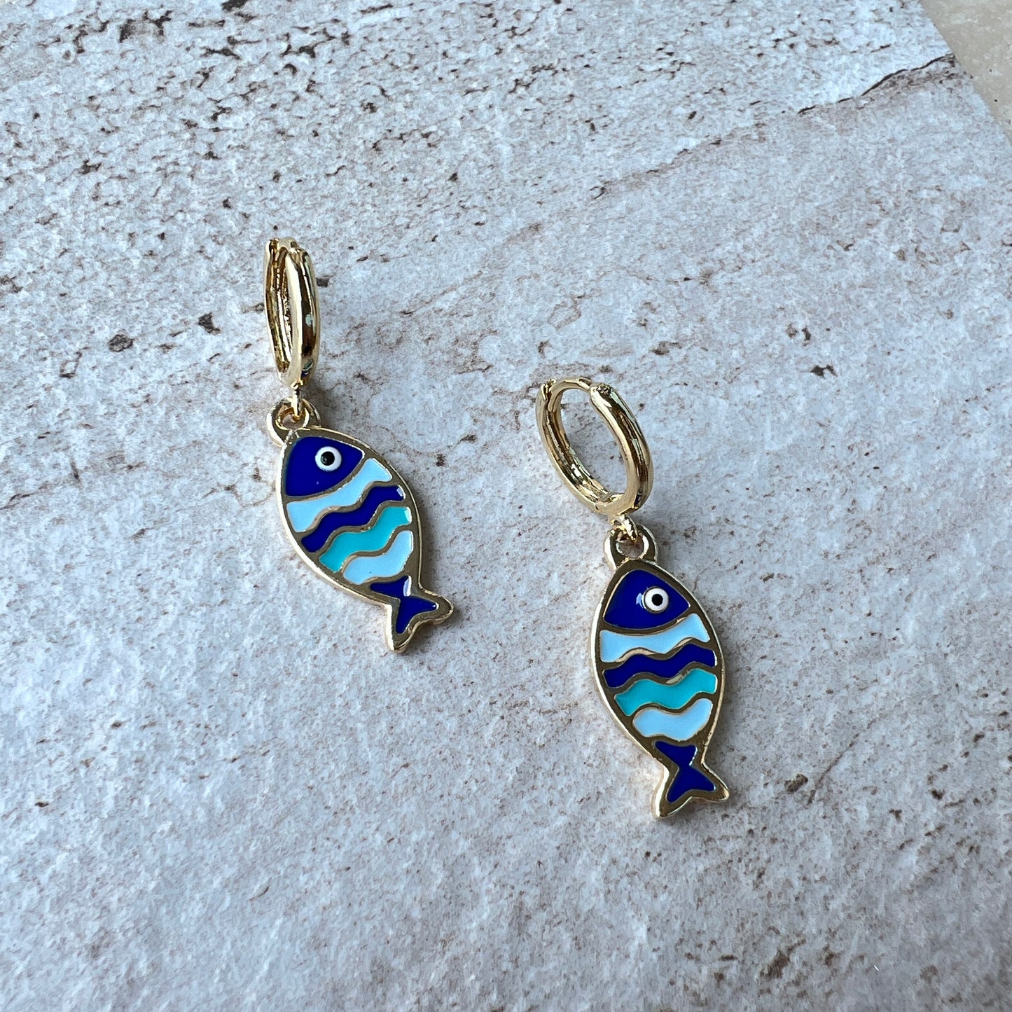 Gold-plated hoop earrings with cobalt, turquoise, and aqua fish charms and evil eye detail
