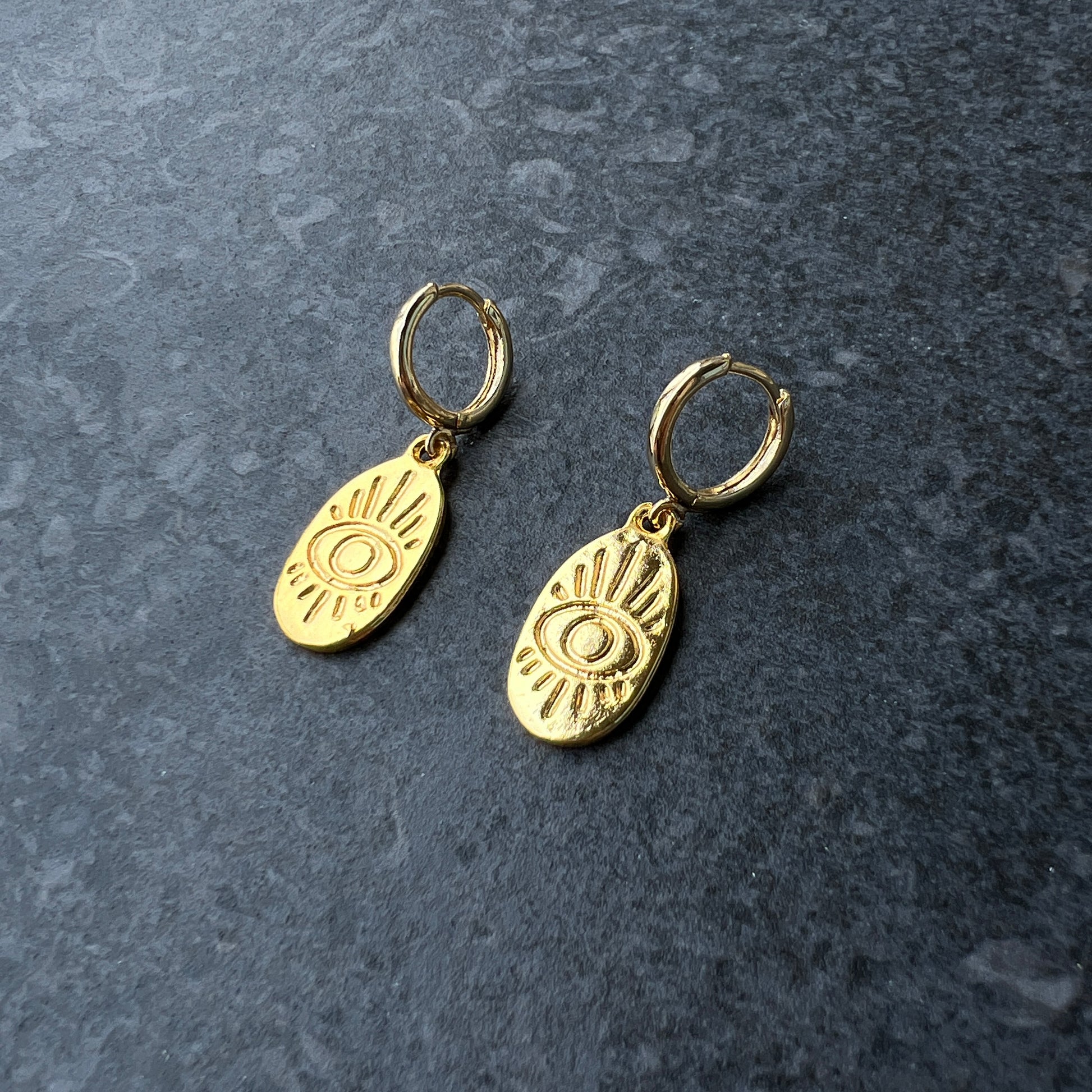 Gold oval evil eye charm hoop earrings with engraved linework