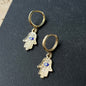 Gold Hamsa hand hoop earrings with blue enamel evil eye charm