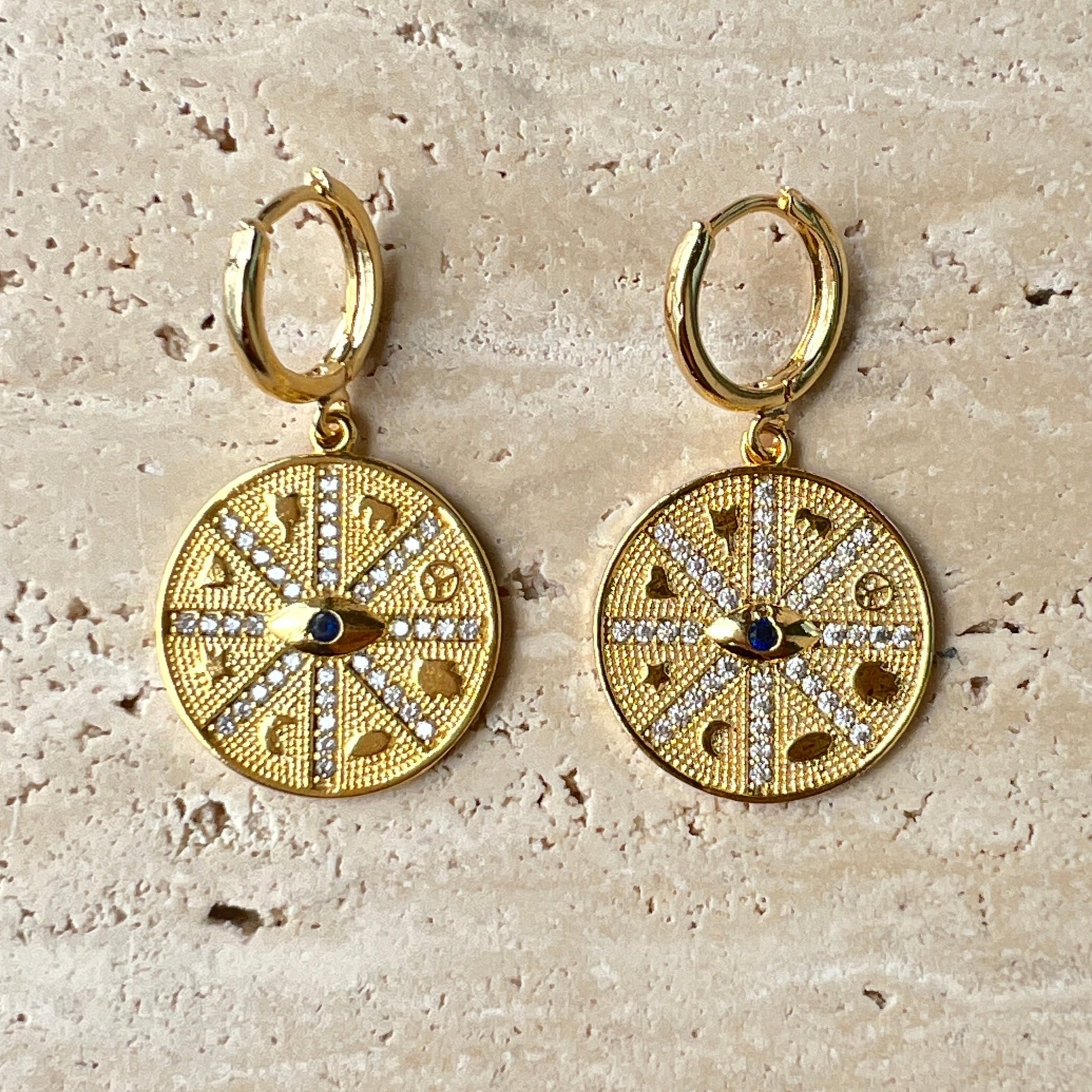 Gold compass medallion hoop earrings with black evil eye stone