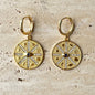 Gold compass medallion hoop earrings with black evil eye stone