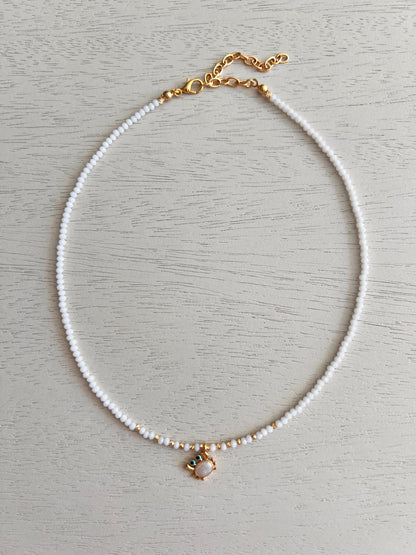 White bead necklace with gold-plated enamel crab charm and blue details
