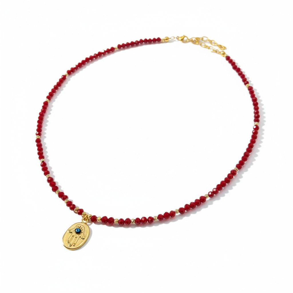 Red crystal necklace with gold-plated Hamsa charm and evil eye detailing