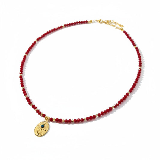 Red crystal necklace with gold-plated Hamsa charm and evil eye detailing